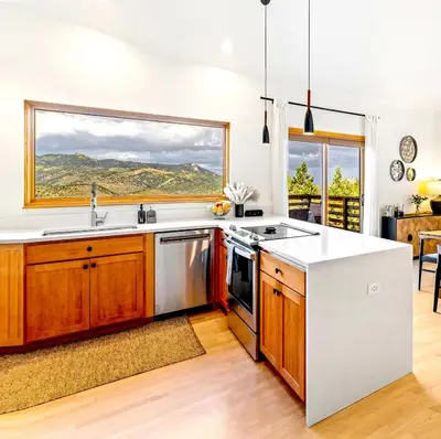 a kitchen with wooden cabinets and a large window at Epic Views - Hot Tub - Starlink Internet - Dogs OK in Evergreen