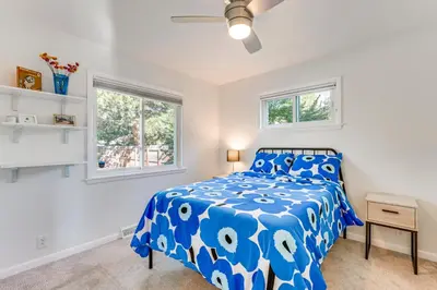 a bedroom with a blue bed and two windows at Central Boulder Home with Outdoor Oasis, Walk to CU! in Boulder