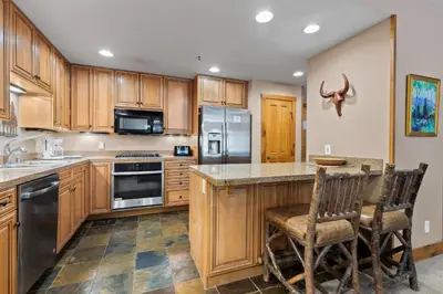 a kitchen with wooden cabinets and stainless steel appliances at Timbers 3064 : 2 in Keystone