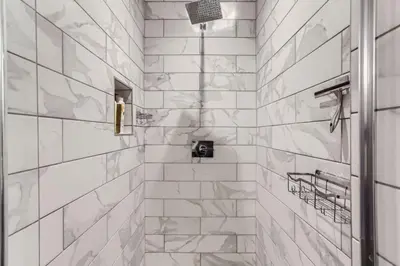 a bathroom with a shower with white marble tiles at Updated Victorian Home in SoBo in Denver