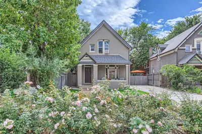 a house with a fence and a yard with flowers at Updated Victorian Home in SoBo in Denver