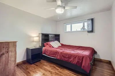 a bedroom with a bed with a red bedspread and a window at Vaulted Ceilings, Natural Light Apt near Olde Town in Arvada