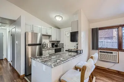 a kitchen with white cabinets and a stainless steel refrigerator at Vaulted Ceilings, Natural Light Apt near Olde Town in Arvada