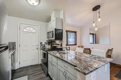 a kitchen with white cabinets and a counter top at Vaulted Ceilings, Natural Light Apt near Olde Town in Arvada