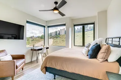 a bedroom with a bed with a ceiling fan and windows at Mtn-View Slopeside Chalet in Granby Ranch! in Granby