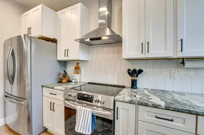 a kitchen with white cabinets and a stainless steel refrigerator at Hot Tub and Mtn-View Rooftop Deck Golden Home in Golden