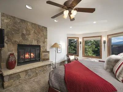 a bedroom with a fireplace and a bed and a ceiling fan at Luxury By The Lake in Dillon