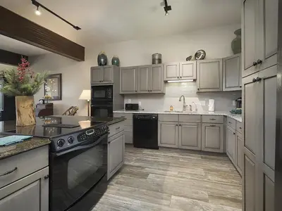 a large kitchen with white cabinets and black appliances at Luxury By The Lake in Dillon