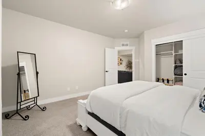 a white bedroom with a bed and a mirror at Scenic Mountain Retreat Golf, Pickleball, Relax in Loveland