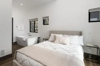 a white bedroom with a bed and a bath tub at Scenic Perch home in Tabernash