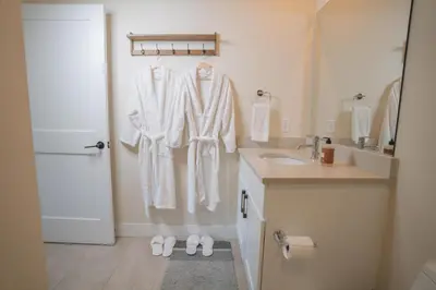 a bathroom with white robes hanging on a wall at WinterPark, Ski, CoffeeBar, Pets and CommunalHotTub in Winter Park