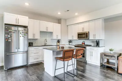 a kitchen with white cabinets and stainless steel appliances at 3 Mi to Dtwn Denver Scenic Townhome with Deck! in Denver