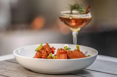 a bowl of food on a table with a glass of wine at The Art Hotel Denver, Curio Collection by Hilton in Denver