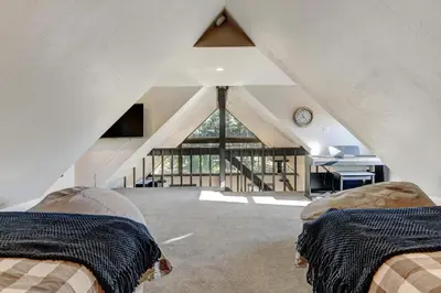 an attic bedroom with two beds and a large window at Silver Lining Circle home in Fraser