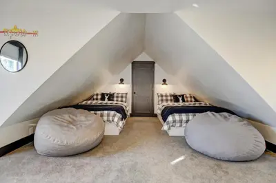 a attic bedroom with two beds and two ottomans at Silver Lining Circle home in Fraser