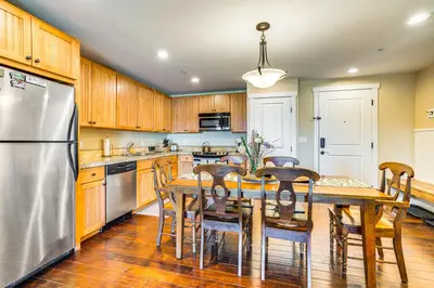 a kitchen with a table with chairs and a refrigerator at Walk to Slopes Granby Condo with Balcony! in Granby