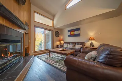 a living room with a leather couch and a fireplace at Ski Run 303 by SummitCove Lodging in Keystone