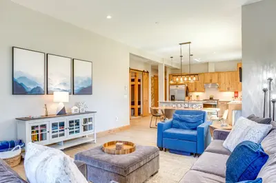 a living room with blue furniture and a kitchen at Modern Condo with Hot Tub 5 Mi to Winter Park! in Fraser
