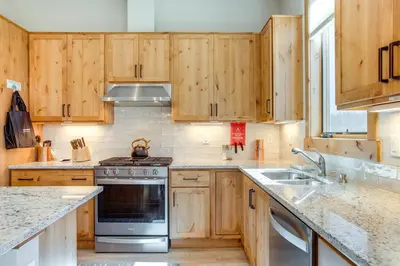 a kitchen with wooden cabinets and a stove top oven at Modern Condo with Hot Tub 5 Mi to Winter Park! in Fraser
