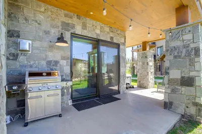 an outdoor kitchen with a stove and a stone wall at Modern Condo with Hot Tub 5 Mi to Winter Park! in Fraser