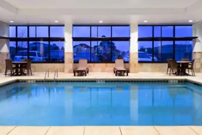 a pool in a hotel with chairs and tables at Baymont by Wyndham Denver International Airport in Denver