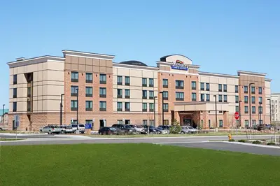 a large brick building with cars parked in a parking lot at Baymont by Wyndham Denver International Airport in Denver