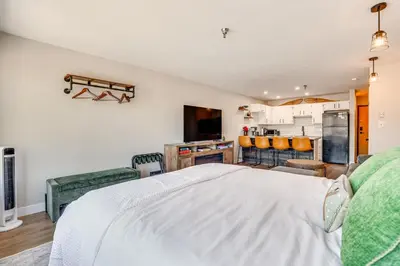 a bedroom with a white bed and a kitchen at Walk to Dtwn Winter Park Studio with Hot Tub Access in Winter Park