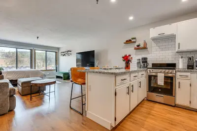 a kitchen with white cabinets and a living room at Walk to Dtwn Winter Park Studio with Hot Tub Access in Winter Park