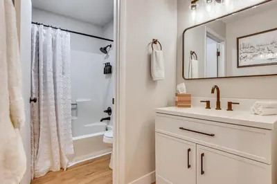 a white bathroom with a sink and a mirror at Walk to Dtwn Winter Park Studio with Hot Tub Access in Winter Park