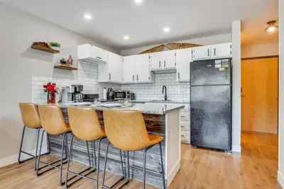 a kitchen with a bar with stools and a refrigerator at Walk to Dtwn Winter Park Studio with Hot Tub Access in Winter Park