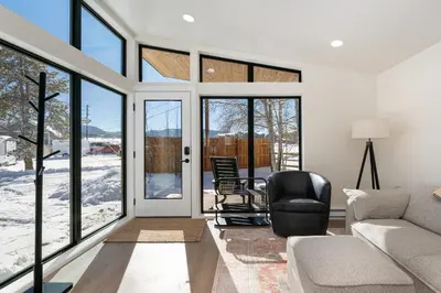 a living room with a couch and chairs and windows at Luxury Modern Tiny Home in Downtown Fraser in Fraser