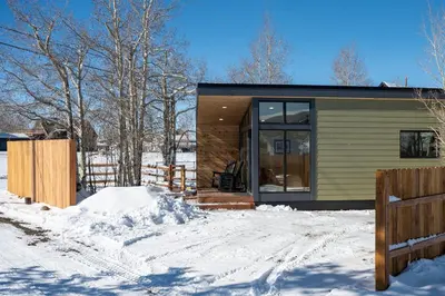 a small house in the snow with a fence at Luxury Modern Tiny Home in Downtown Fraser in Fraser