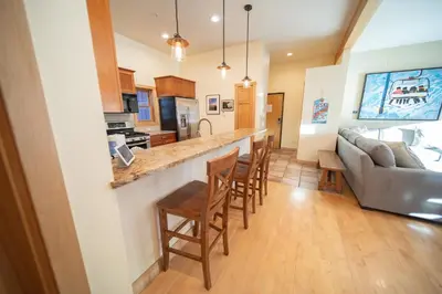 a kitchen and living room with a bar and a couch at Mill Creek 201 by SummitCove Lodging in Keystone