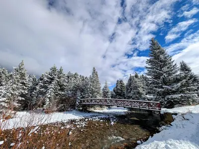 a red bridge over a river in a snow covered forest at Ironwood 2996 by SummitCove Lodging in Keystone