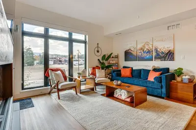 a living room with a blue couch and a table at Mountain-View Condo in Downtown Winter Park! in Winter Park