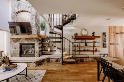 a living room with a spiral staircase and a fireplace at Alpine Hideaway with Free Shuttle - Wildernest in Silverthorne