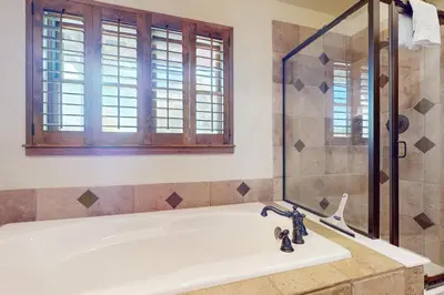 a bath tub with a shower and a sink at Rendezvous Royalty in Fraser