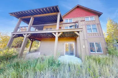a house with a large deck on top of it at Rendezvous Royalty in Fraser