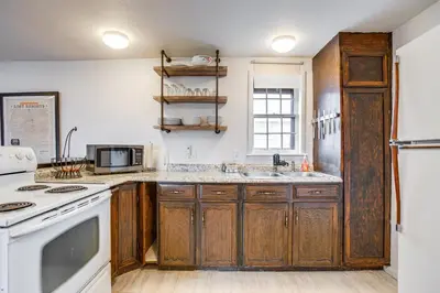 a kitchen with wooden cabinets and a white stove top oven at Hike, Ski and More Walkable Downtown Granby Home in Granby