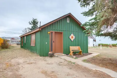 a green building with a wooden door and a bench at Hike, Ski and More Walkable Downtown Granby Home in Granby