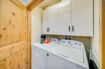a washer and dryer in a laundry room with white cabinets at Downtown WP Condo with Pool Steps to Concert Venue! in Winter Park