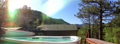 a boat sitting next to a house with a rainbow at Creekside Craftsman Cabin with Jacuzzi - Alpine Splendor 6 Mins to downtown in Boulder