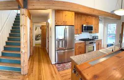 a kitchen with a staircase and a stainless steel refrigerator at Creekside Craftsman Cabin with Jacuzzi - Alpine Splendor 6 Mins to downtown in Boulder