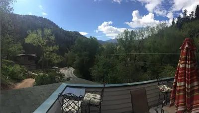 a balcony with a view of a road and trees at Creekside Craftsman Cabin with Jacuzzi - Alpine Splendor 6 Mins to downtown in Boulder