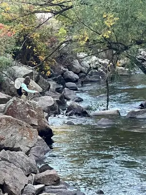 a person is standing on rocks near a river at Creekside Craftsman Cabin with Jacuzzi - Alpine Splendor 6 Mins to downtown in Boulder