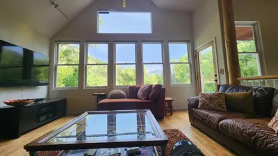 a living room with a couch and a glass table at Creekside Craftsman Cabin with Jacuzzi - Alpine Splendor 6 Mins to downtown in Boulder