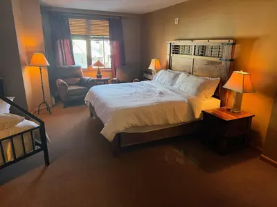 a bedroom with a large bed and a chair at Ski-In Ski-Out Condo at Zephyr Mountain Lodge 1518 in Winter Park