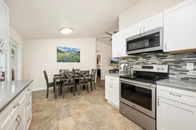 a kitchen with white cabinets and a table with chairs at RMNP Retreat Group Friendly Home near Estes Park in Loveland