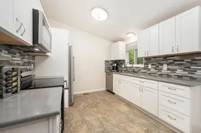 a kitchen with white cabinets and stainless steel appliances at RMNP Retreat Group Friendly Home near Estes Park in Loveland