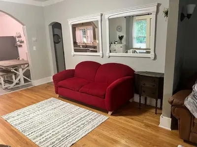 a red couch in a living room with two windows at Walk to Dining Breweries and Shops Plus New Hot Tub in Louisville